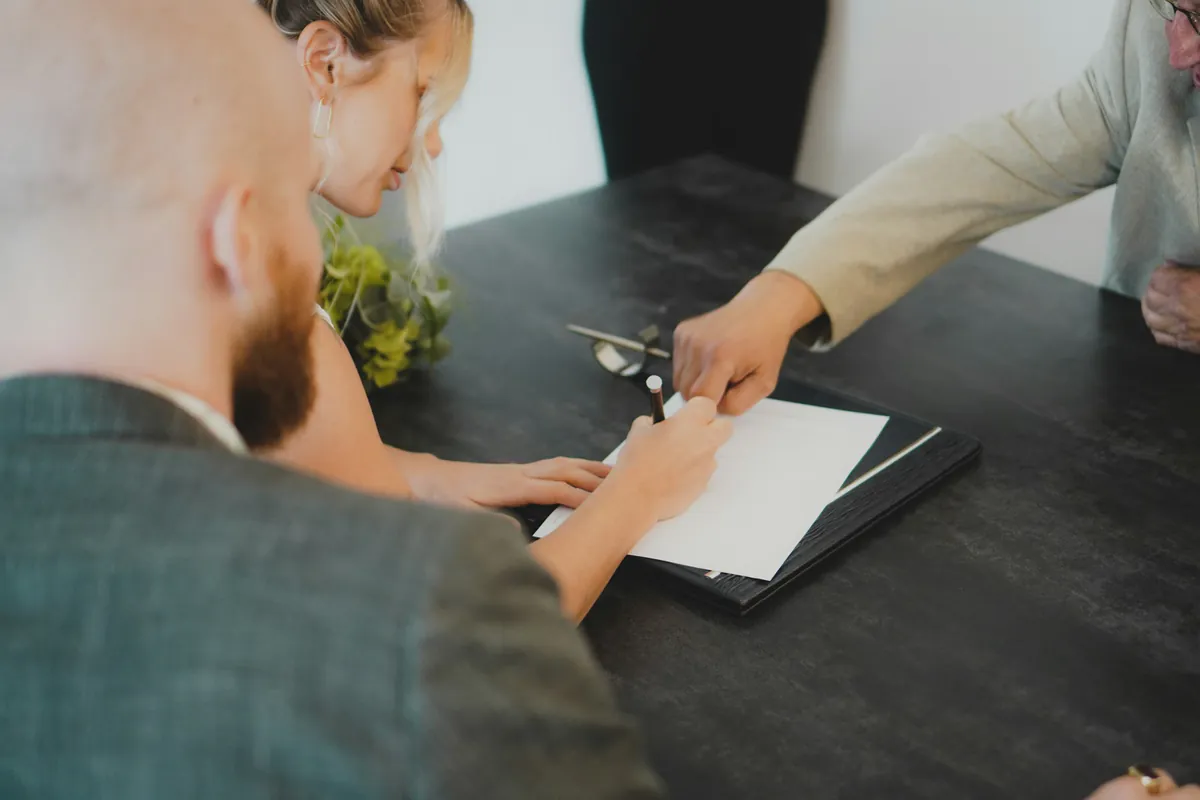 Couple reviewing and signing estate paperwork at a desk with an advisor